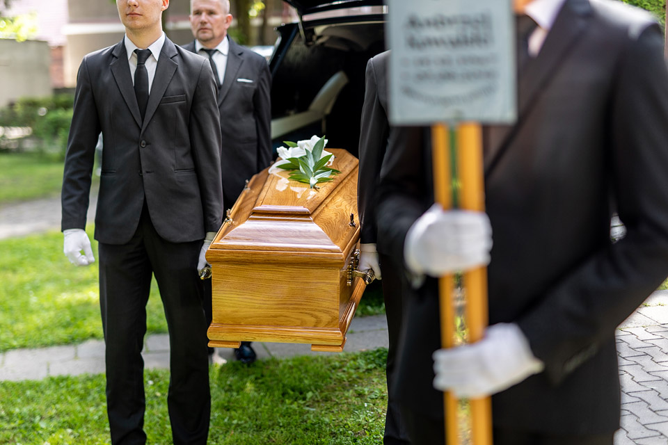Pracownicy firmy Archon niosący trumnę do kaplicy podczas ceremonii pogrzebowej.