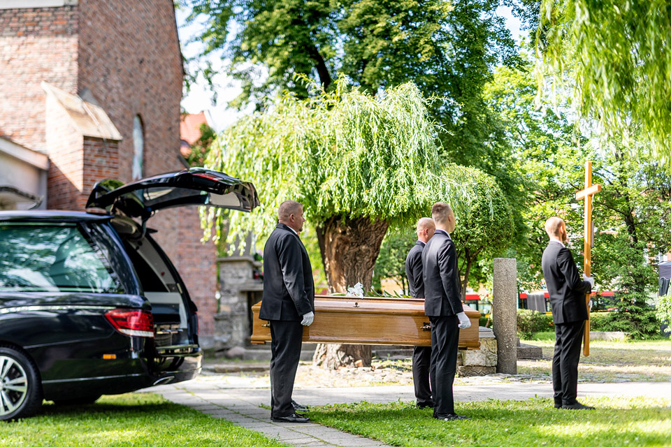 Pracownicy firmy Archon niosą trumnę obok kaplicy podczas ceremonii pogrzebowej.